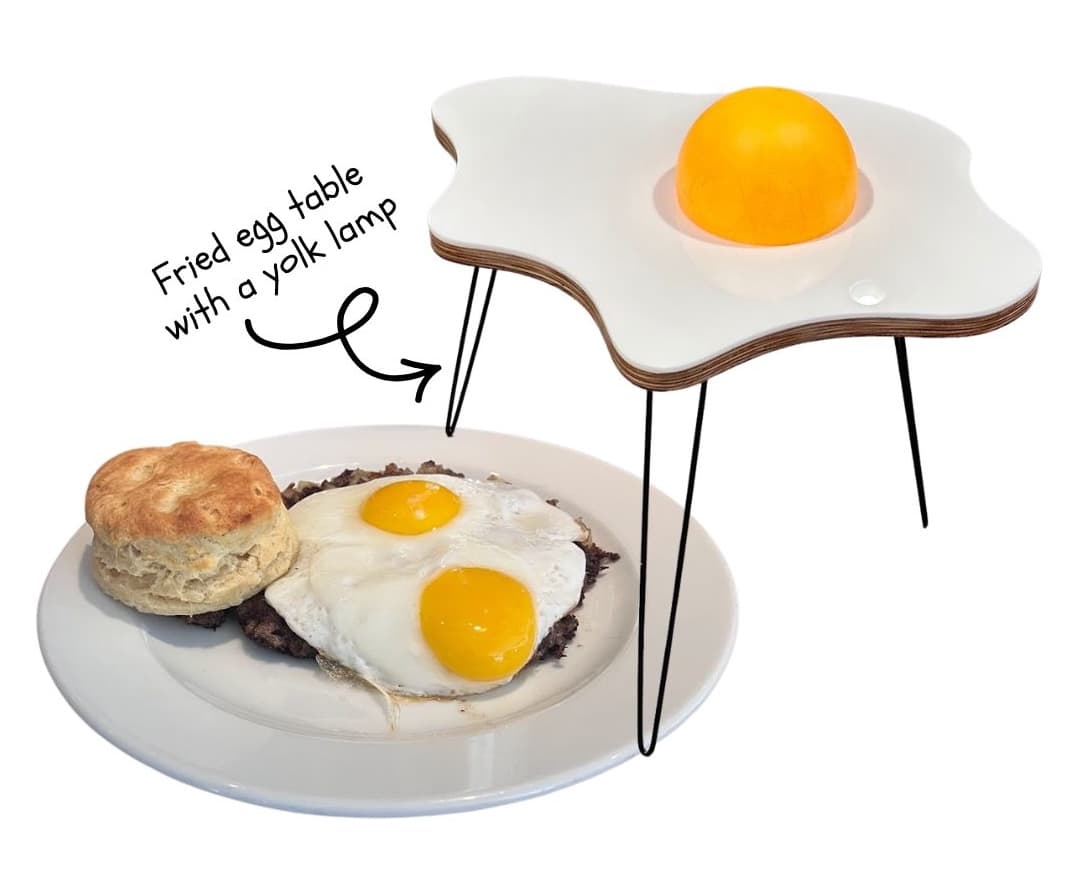 A fried-egg-shaped side table prototype with sunny-side-up eggs on a plate beneath it